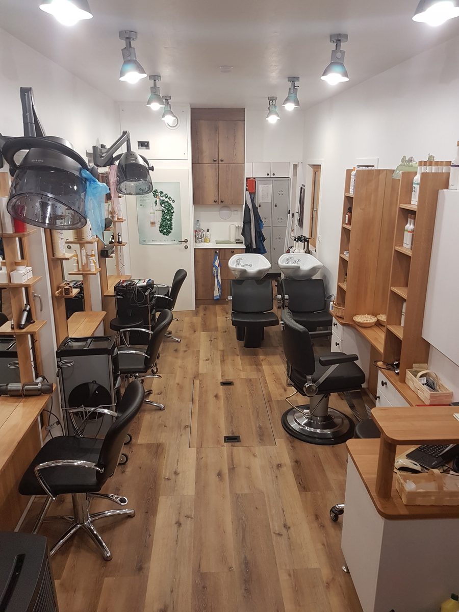 Der fertige Salon von innen: Friseurstühle, Spiegel, Regale, Holzboden.