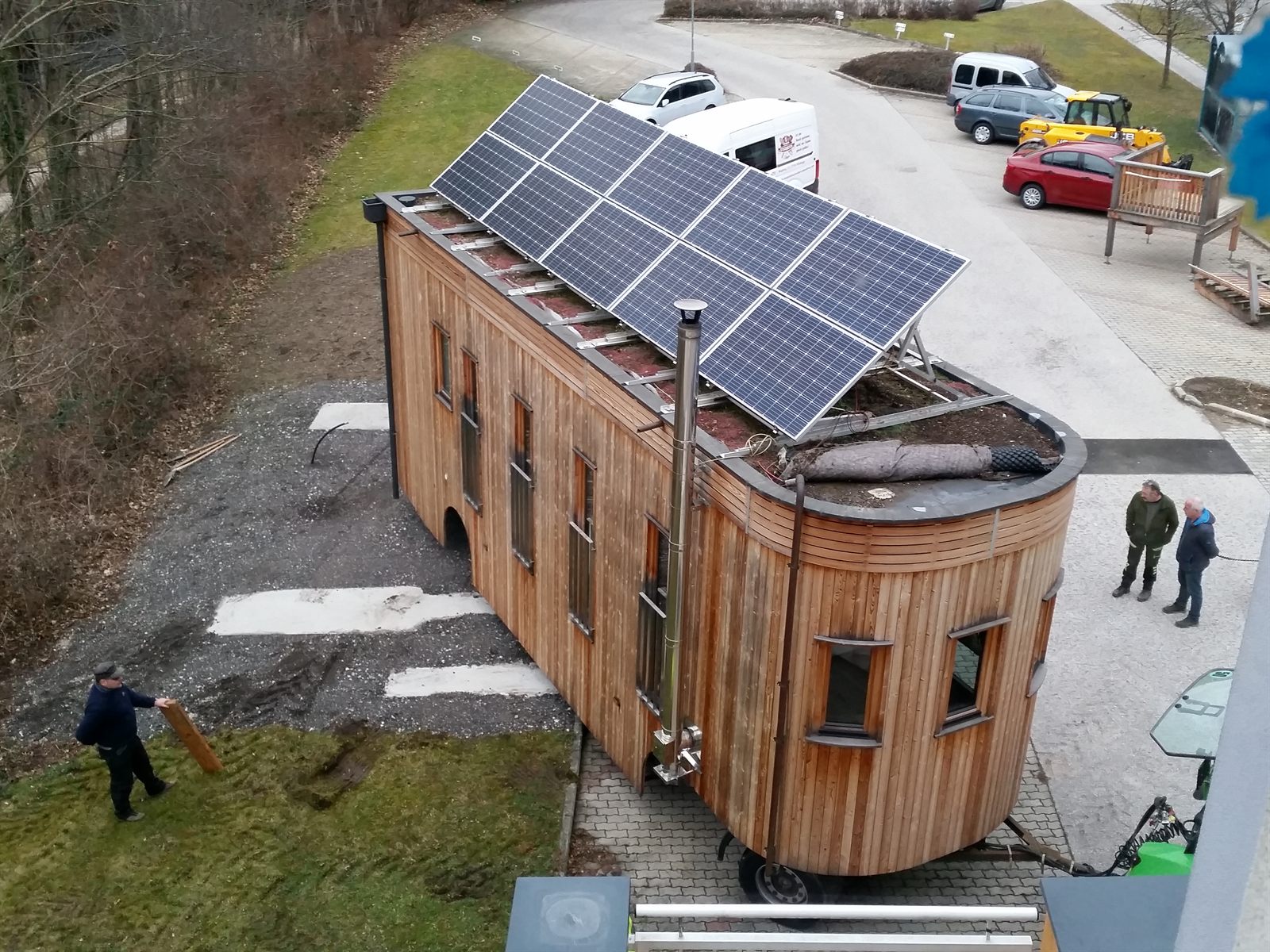 Der Wagon von oben: acht Photovoltaikmodule auf einem Gestell über dem bepflanzten Gründach, daneben das Kaminrohr.