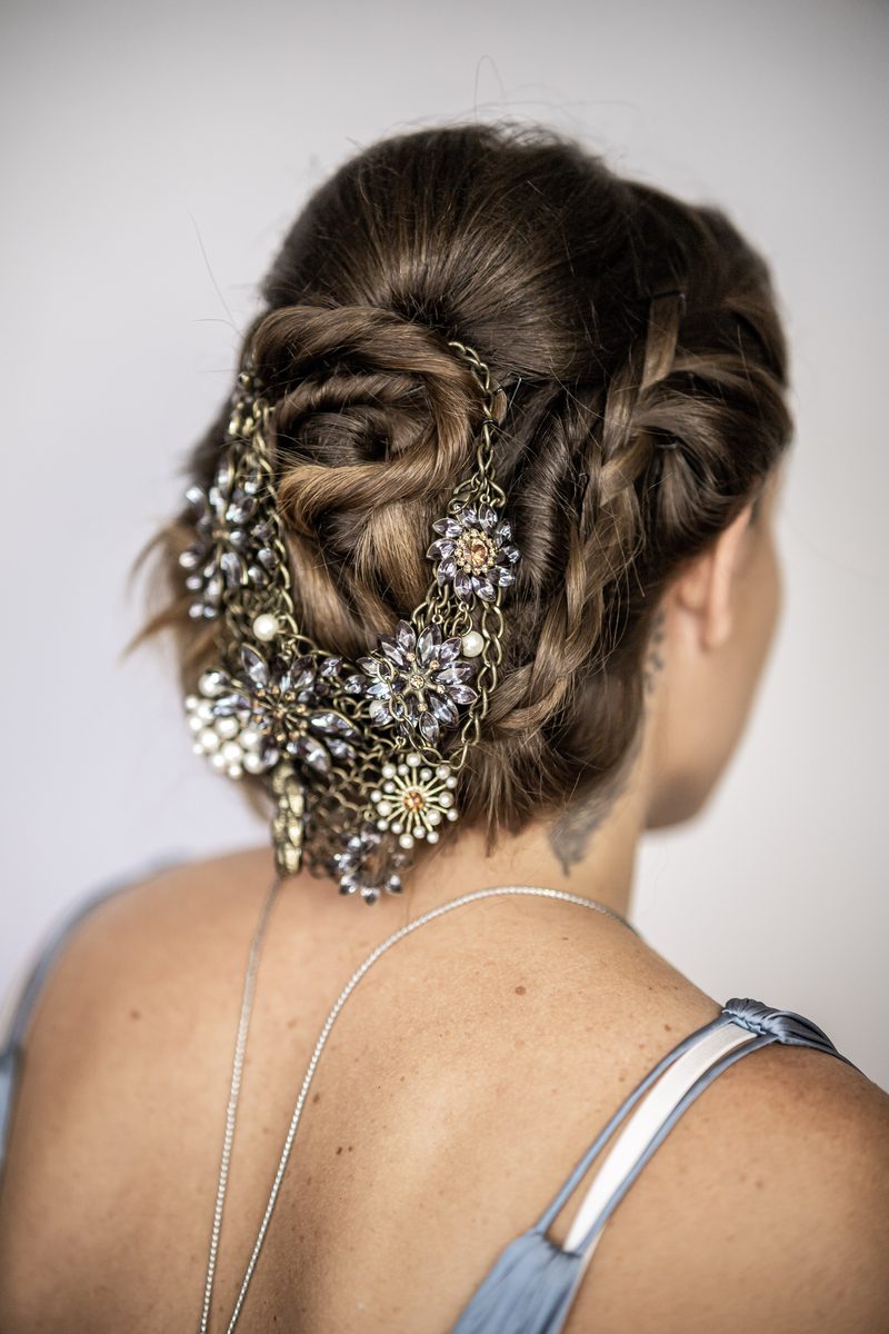 Geflochtenes Haar mit goldenem Haarschmuck und kleinen Blüten durchzogen.