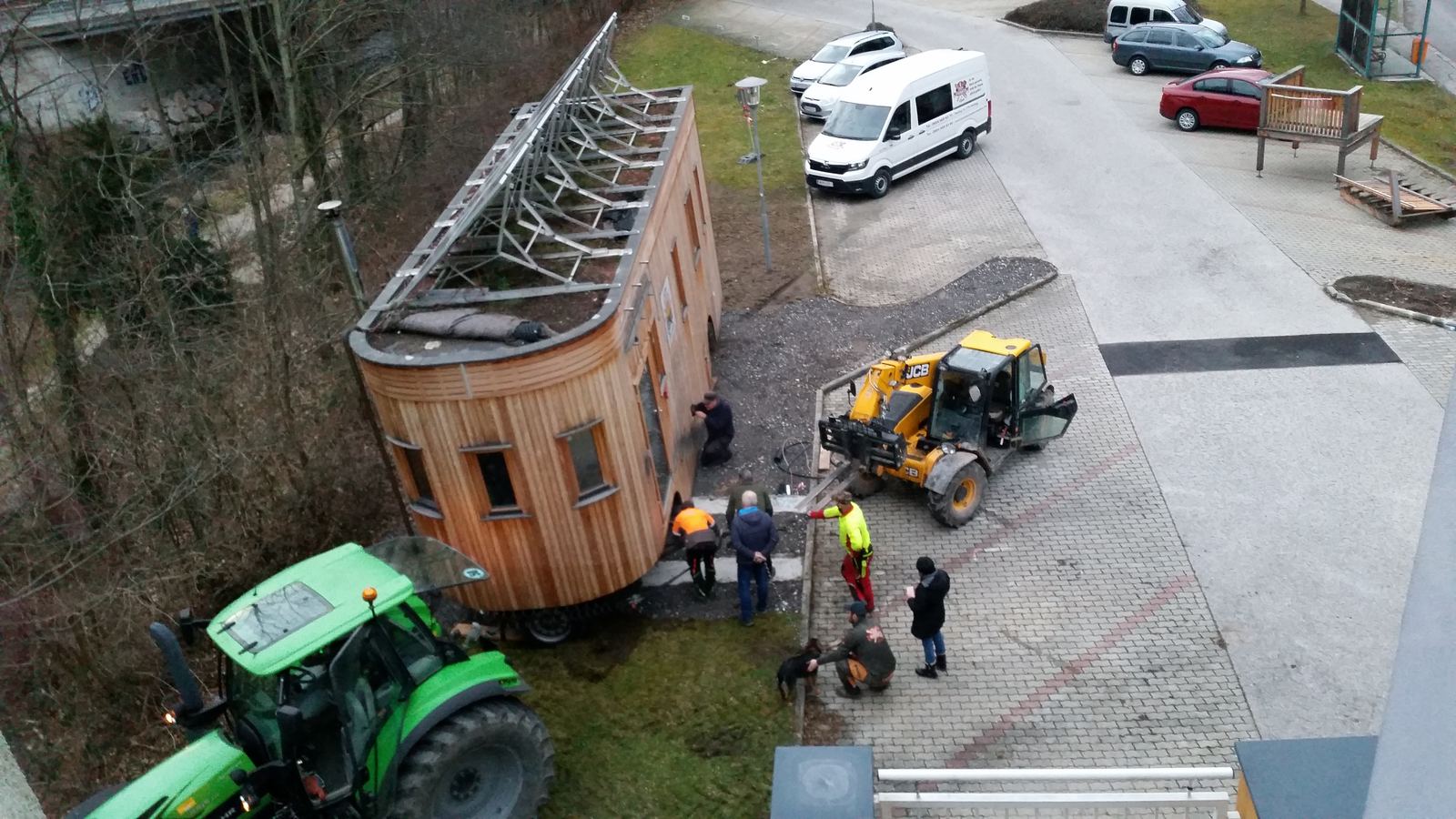 Ein gelber Teleskoplader steht neben dem Wagon, Arbeiter in Warnwesten daneben.